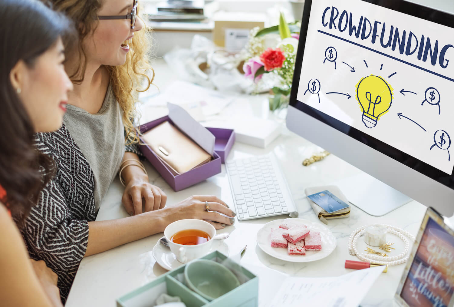 Two young women looking at at crowdfunding graph on a monitor