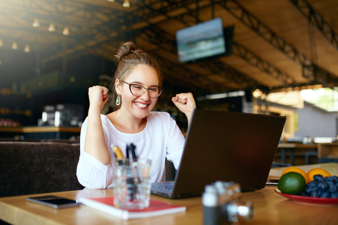 Woman on her laptop celebrating a fundraising campaign win