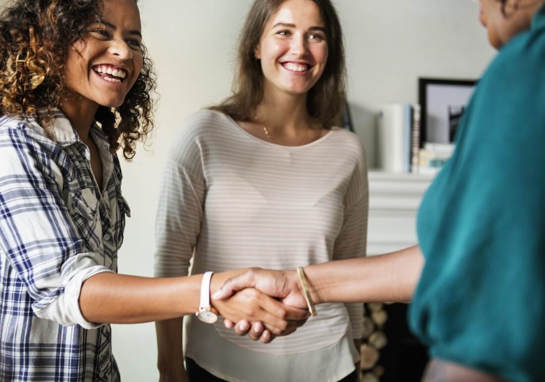 Woman smiling and shaking hands with a coworker