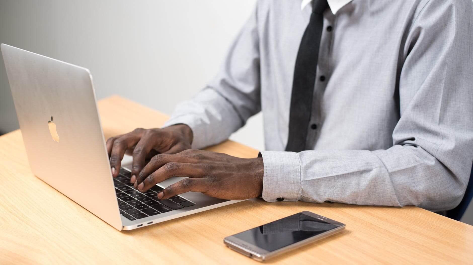 Black individual typing on laptop