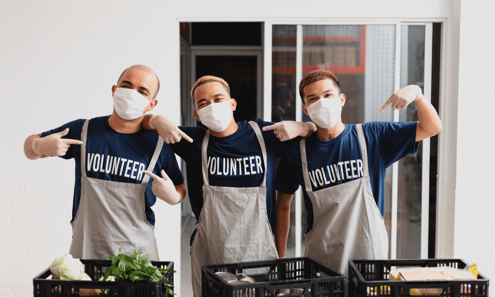 Three male volunteers serving food at a fundraiser