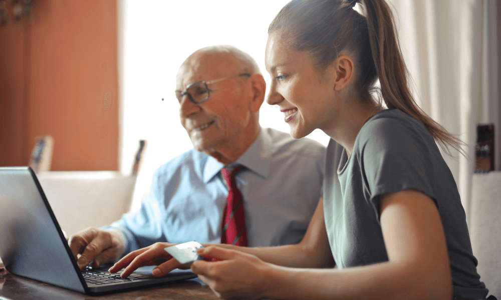 Young woman helping senior man make an online venmo donation