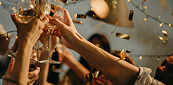 Hands raising champagne glasses amid confetti