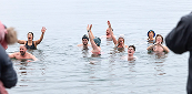 Group of people cheering in cold water for a polar plunge