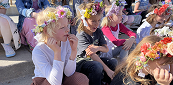 Children wearing flower crowns seated outdoor