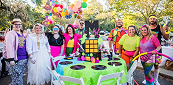 Group in neon 80s outfits around a themed table